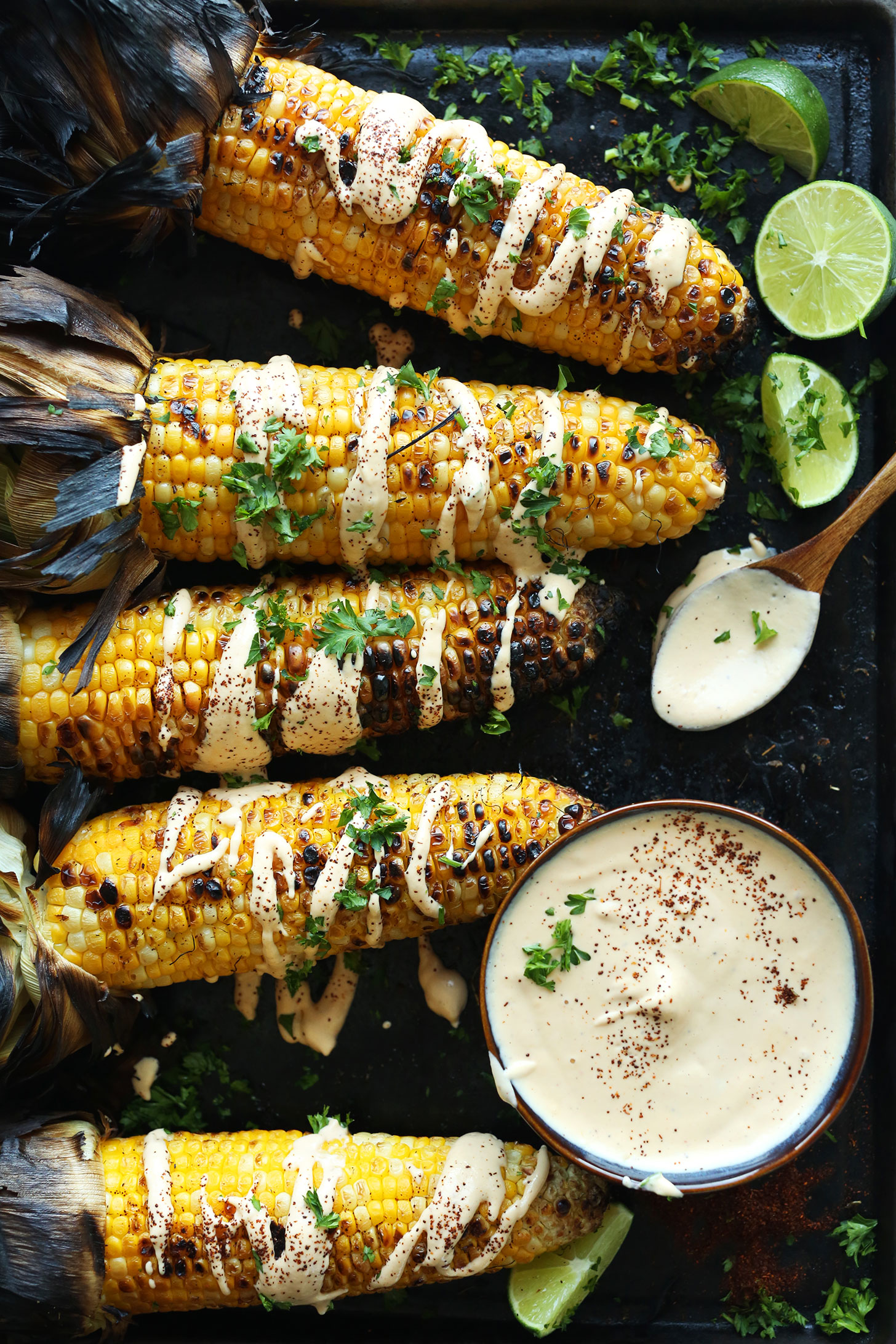 Baking sheet of grilled corn cobs with vegan aioli