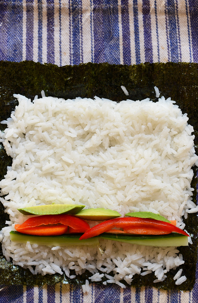 Nori sheet topped with rice and vegetables for making homemade sushi