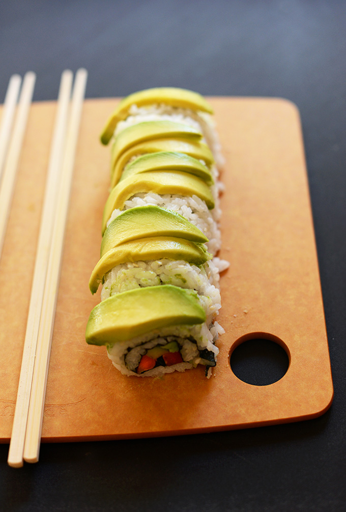 Inside Out Avocado Sushi Roll on a on a cutting board with chopsticks