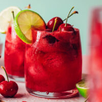 Glass of sparkling cherry limeade garnished with a lime slice and fresh cherries